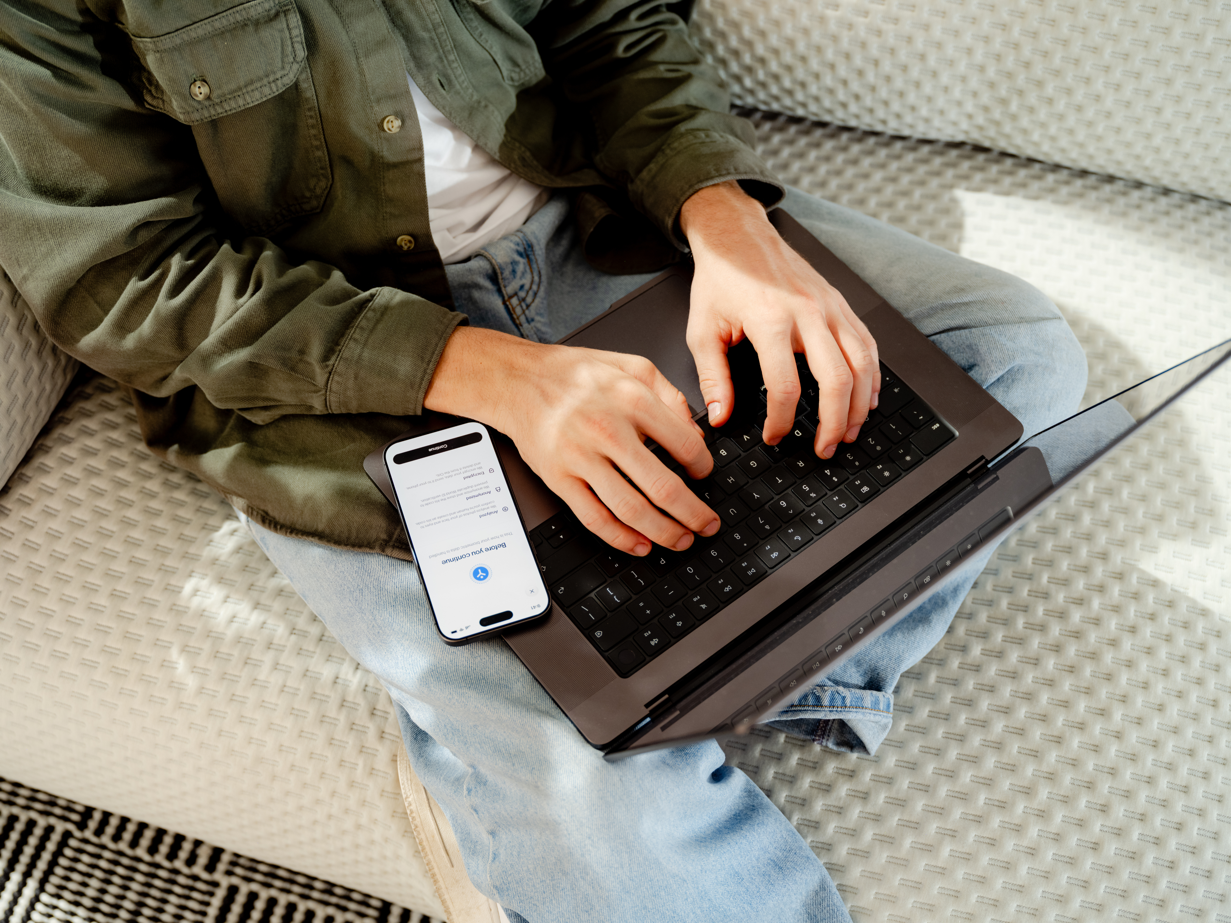 A person using a laptop beside a World ID verification on their phone