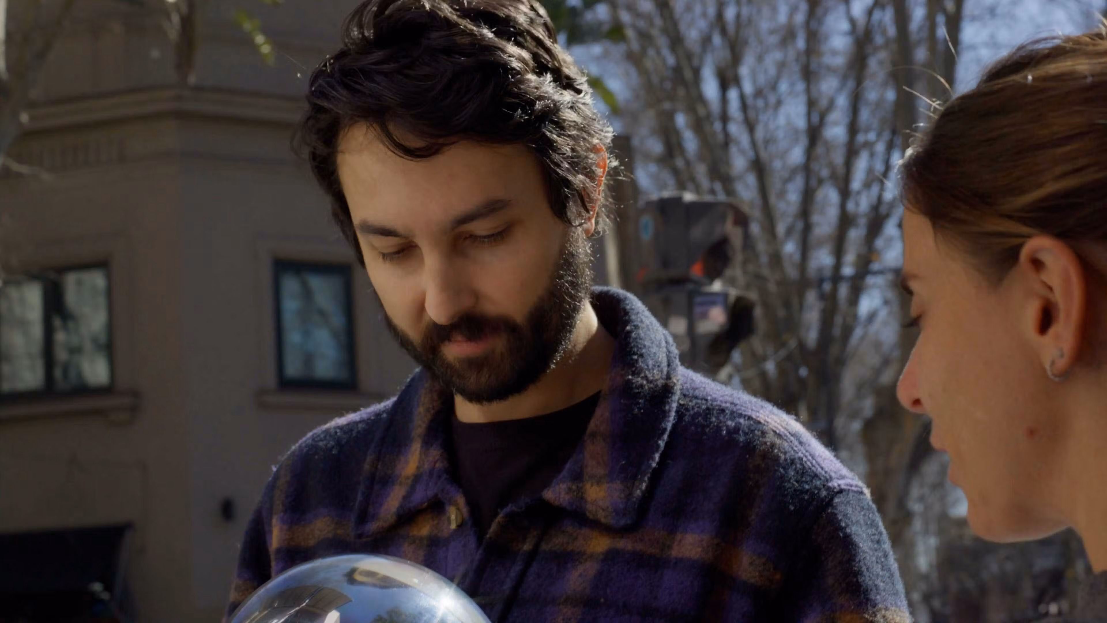 Two people engaging with the Orb outdoors, one person looking at the Orb with a thoughtful expression.