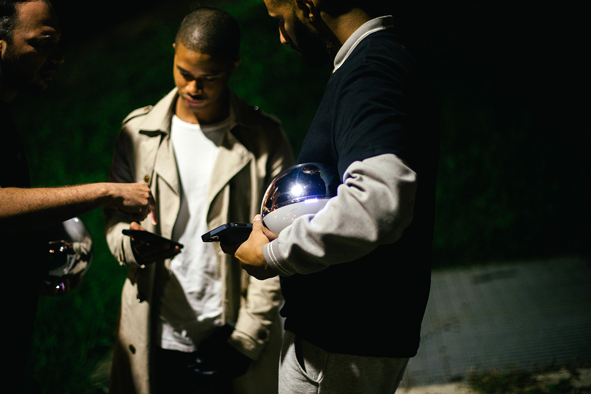 Three individuals engaging with the Orb in a nighttime outdoor setting, highlighting community interaction and empowerment through biometric verification.