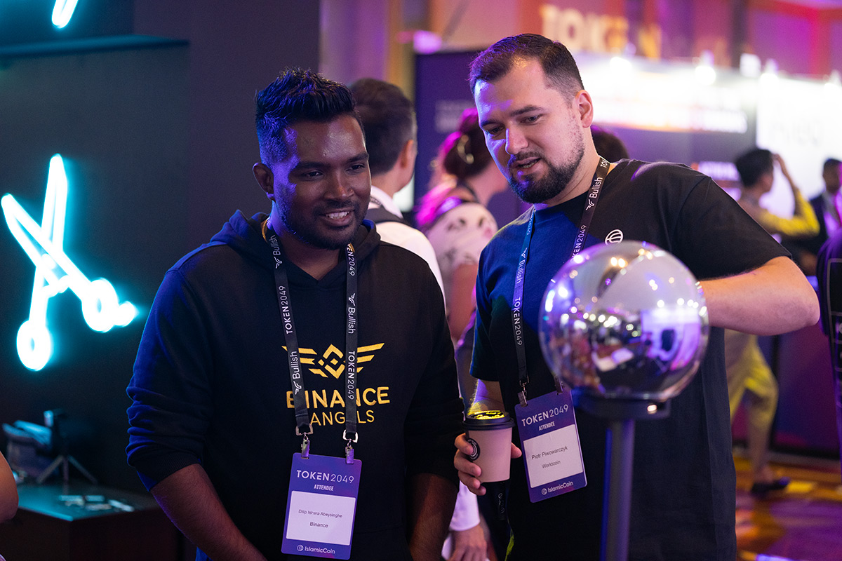 Two individuals engaging with the Orb at a conference, discussing its features, with a vibrant background.