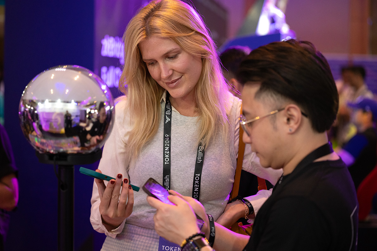 Two people interacting with a smartphone and the Orb at an event, showcasing community engagement and technological empowerment.