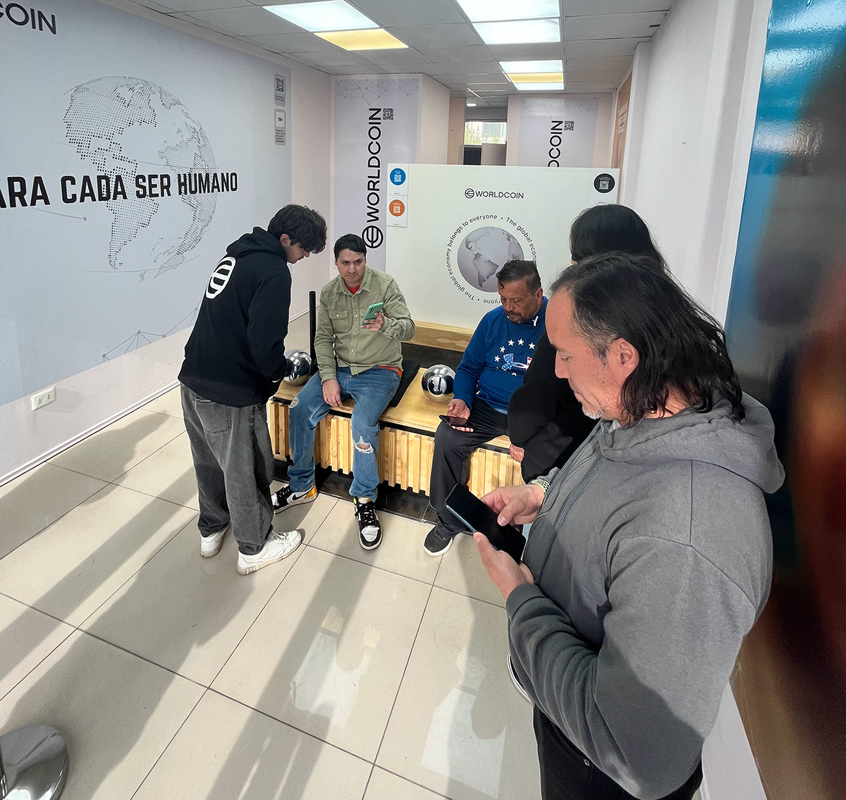 A group of people engaging with the Orb and using devices in a bright, welcoming space that promotes community and technology.