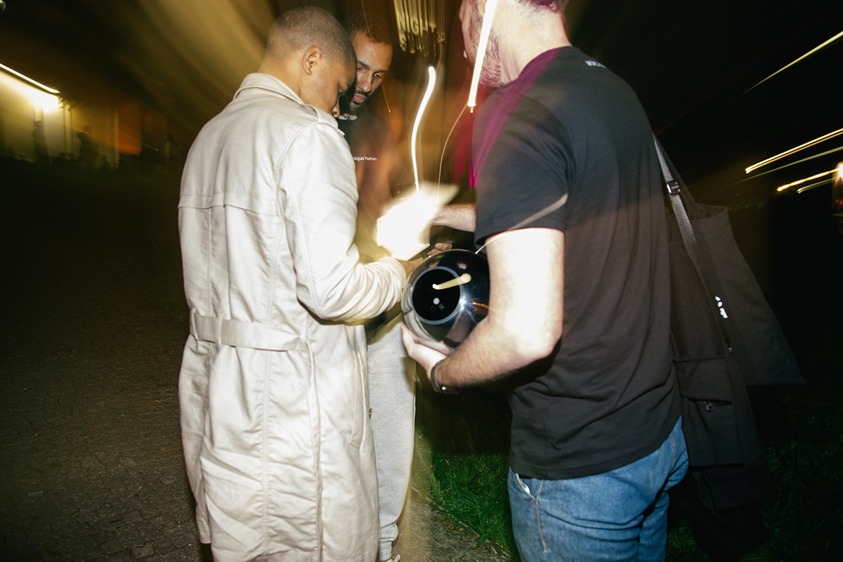Two individuals verifying with the Orb in a lively outdoor setting at night, showcasing community engagement and innovation.
