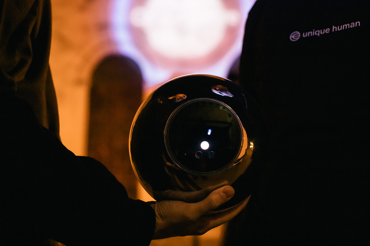 A person holding an Orb in a warmly lit environment, showcasing the device's sleek design and interface.