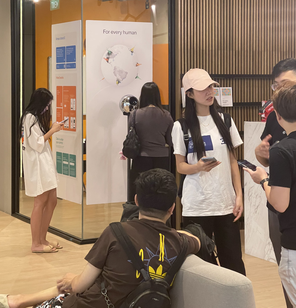 People interacting in a modern space with an Orb for biometric verification and informational displays in the background.