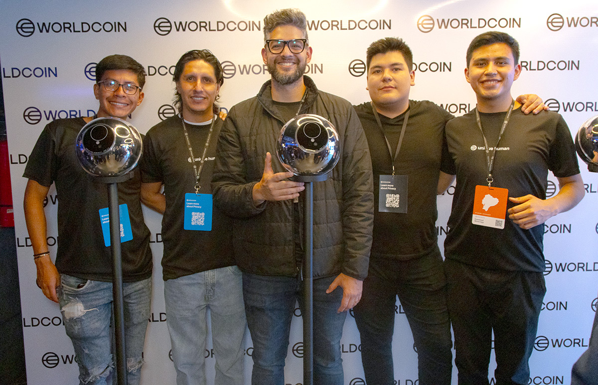 Five individuals pose together at a Worldcoin event, standing in front of Orbs, representing community engagement and technological innovation.