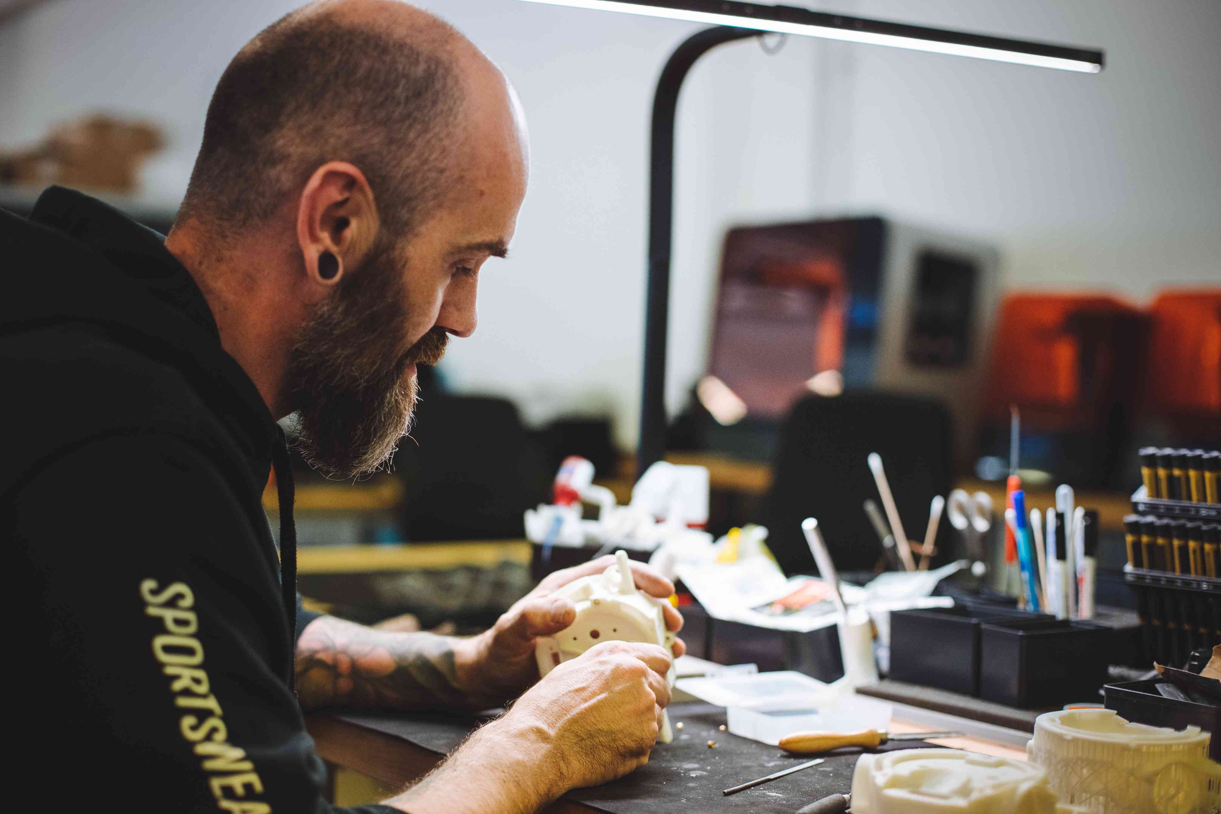 A focused individual working on a project at a desk, surrounded by tools and equipment. The scene highlights craftsmanship and dedication in a creative environment.