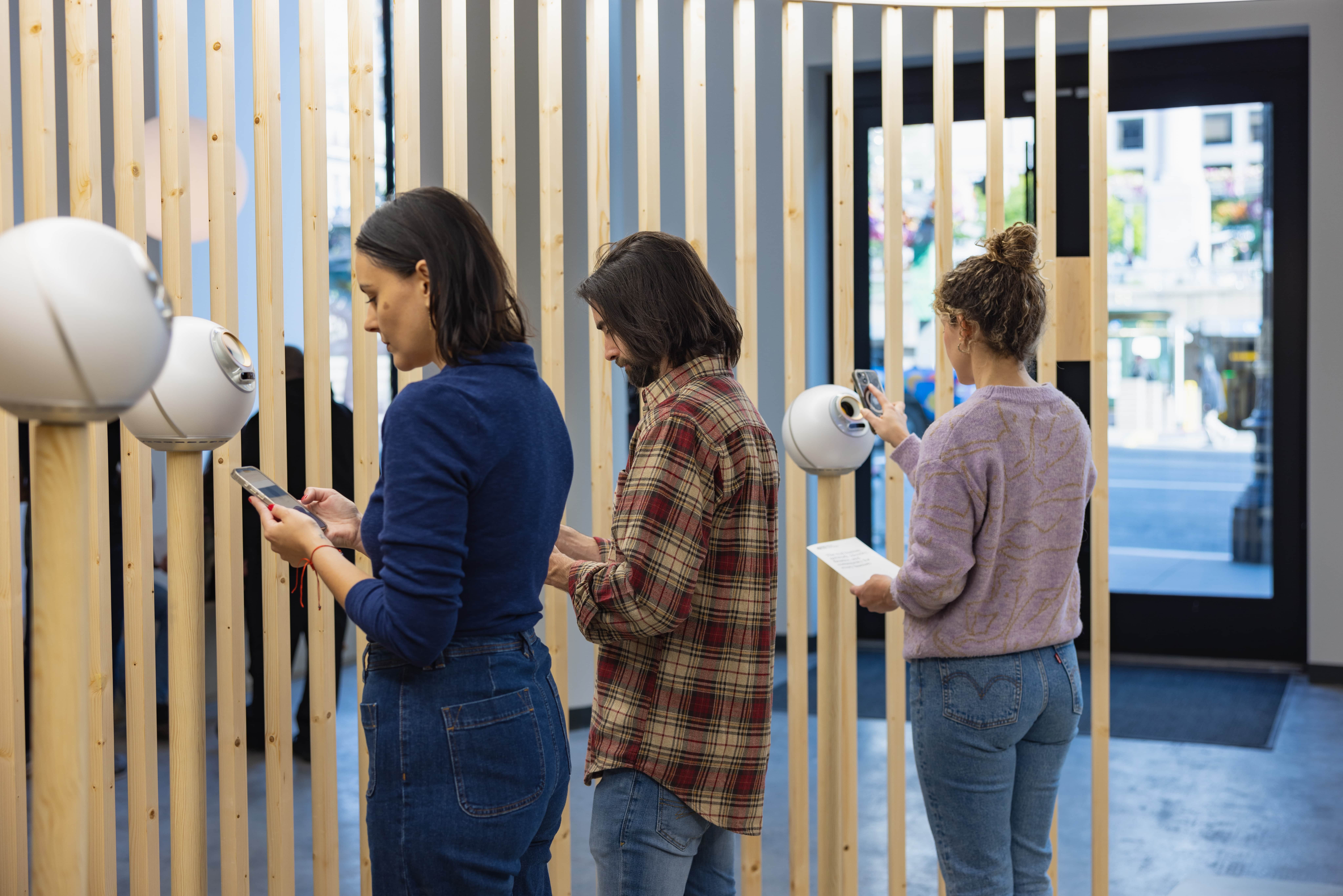 Three people using their phones while getting verified with the Orb at the World flagship store.