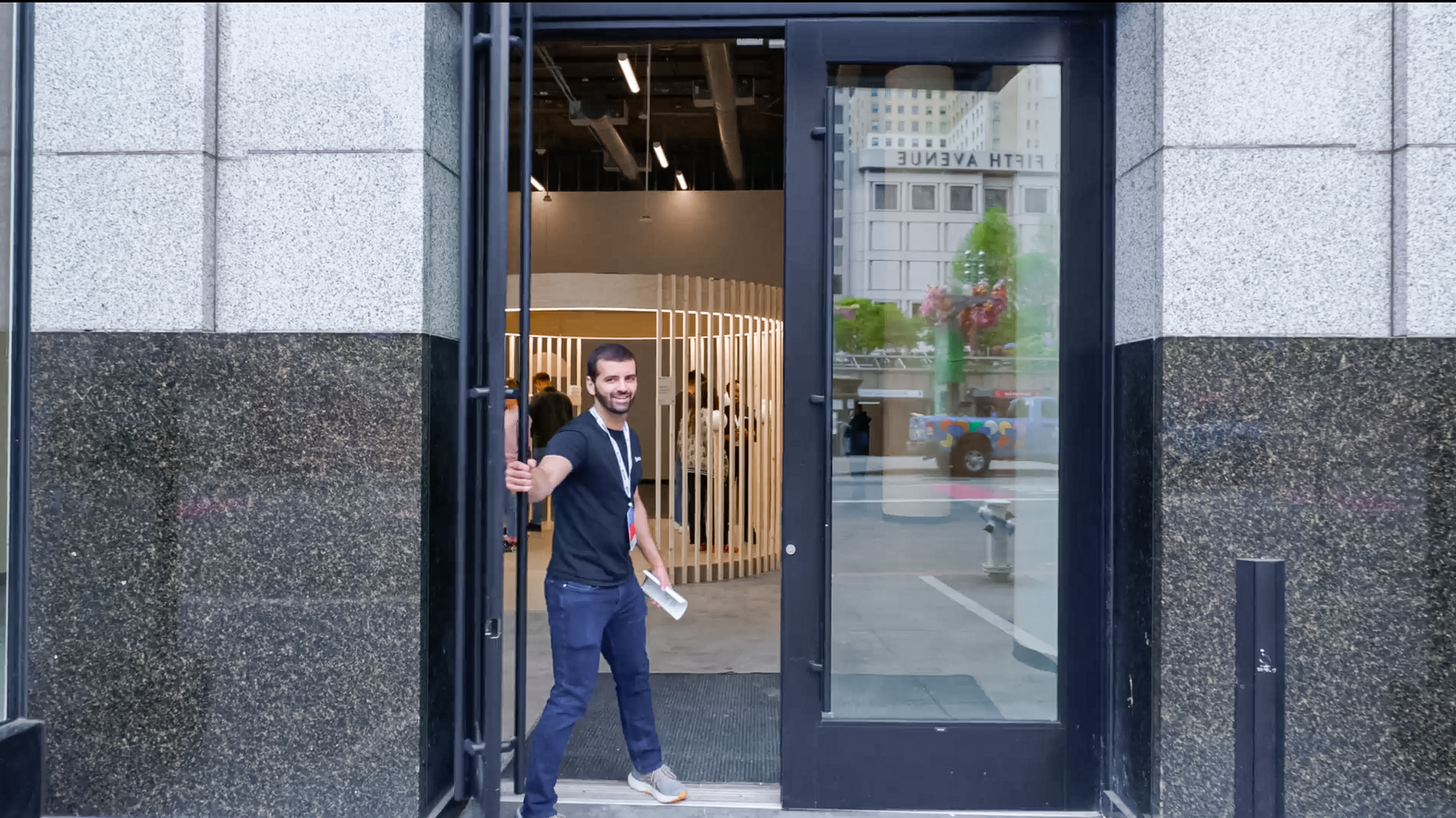 A person holding the door open at the entrance of the World flagship store in Union Square, San Francisco.