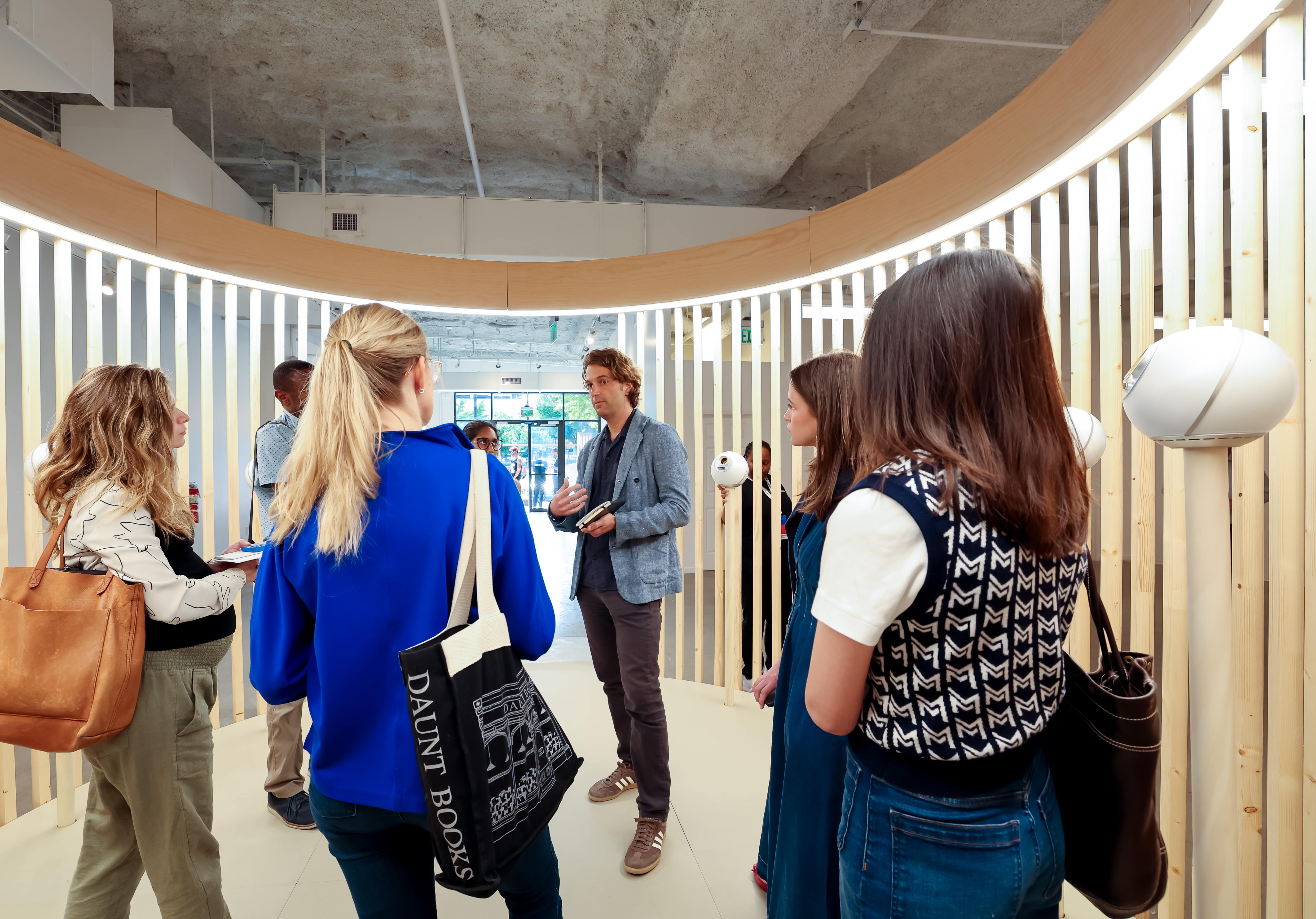 A group of people engages in conversation inside a modern space featuring wooden slats and Orbs, discussing biometric verification technology.
