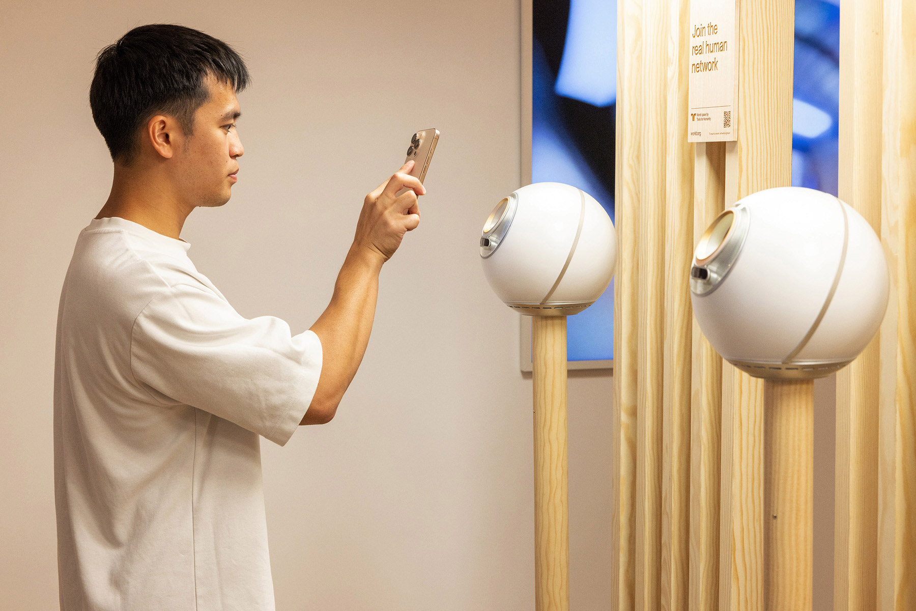 A person uses a smartphone to interact with the Orbs for biometric verification.