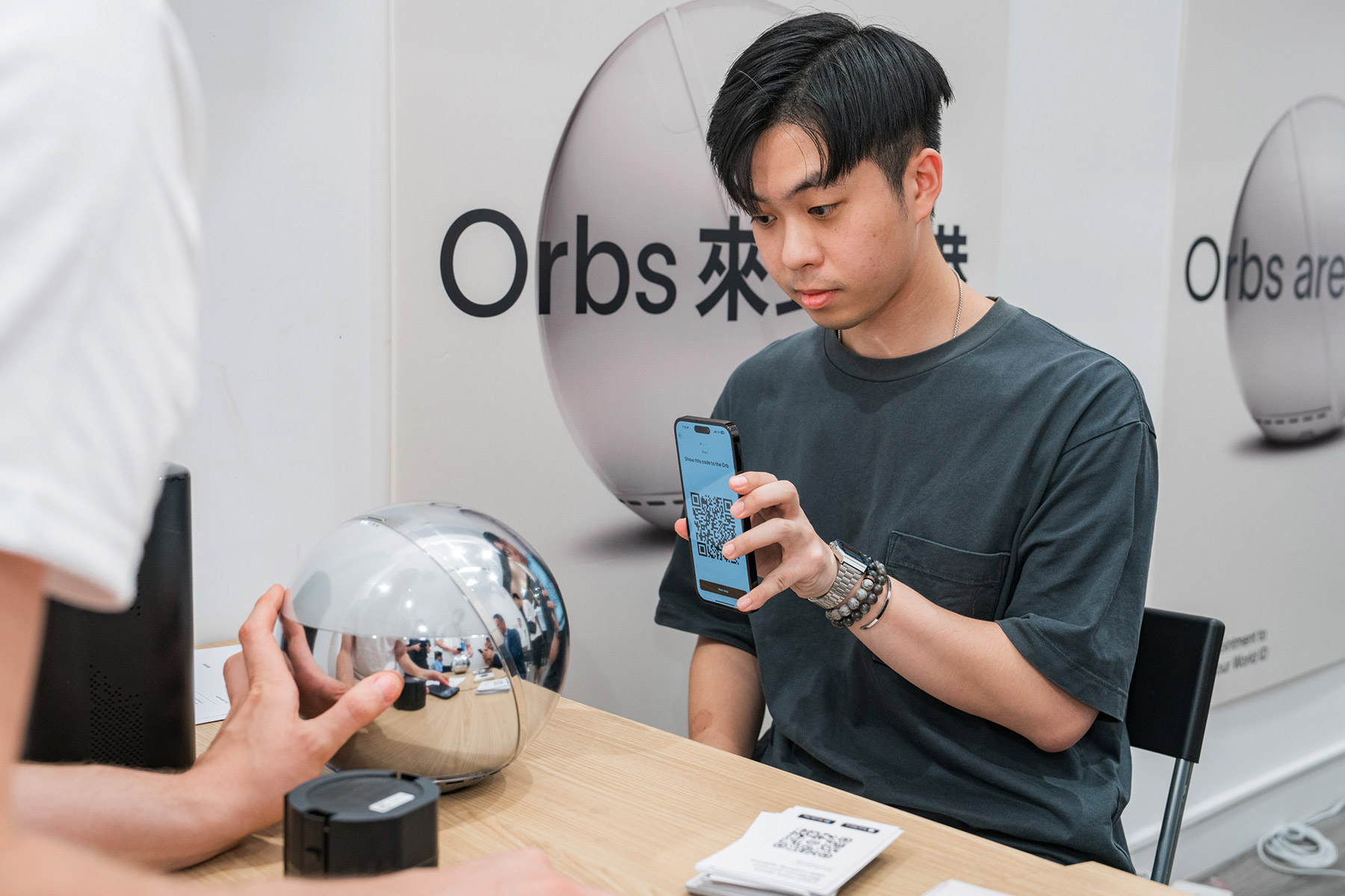 A young person using a smartphone to scan a QR code while interacting with an Orb.