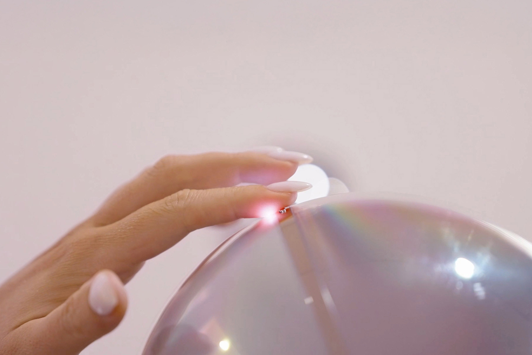 A hand is gently placing a finger on the Orb, which reflects light in a metallic sheen. The scene suggests a moment of biometric verification.