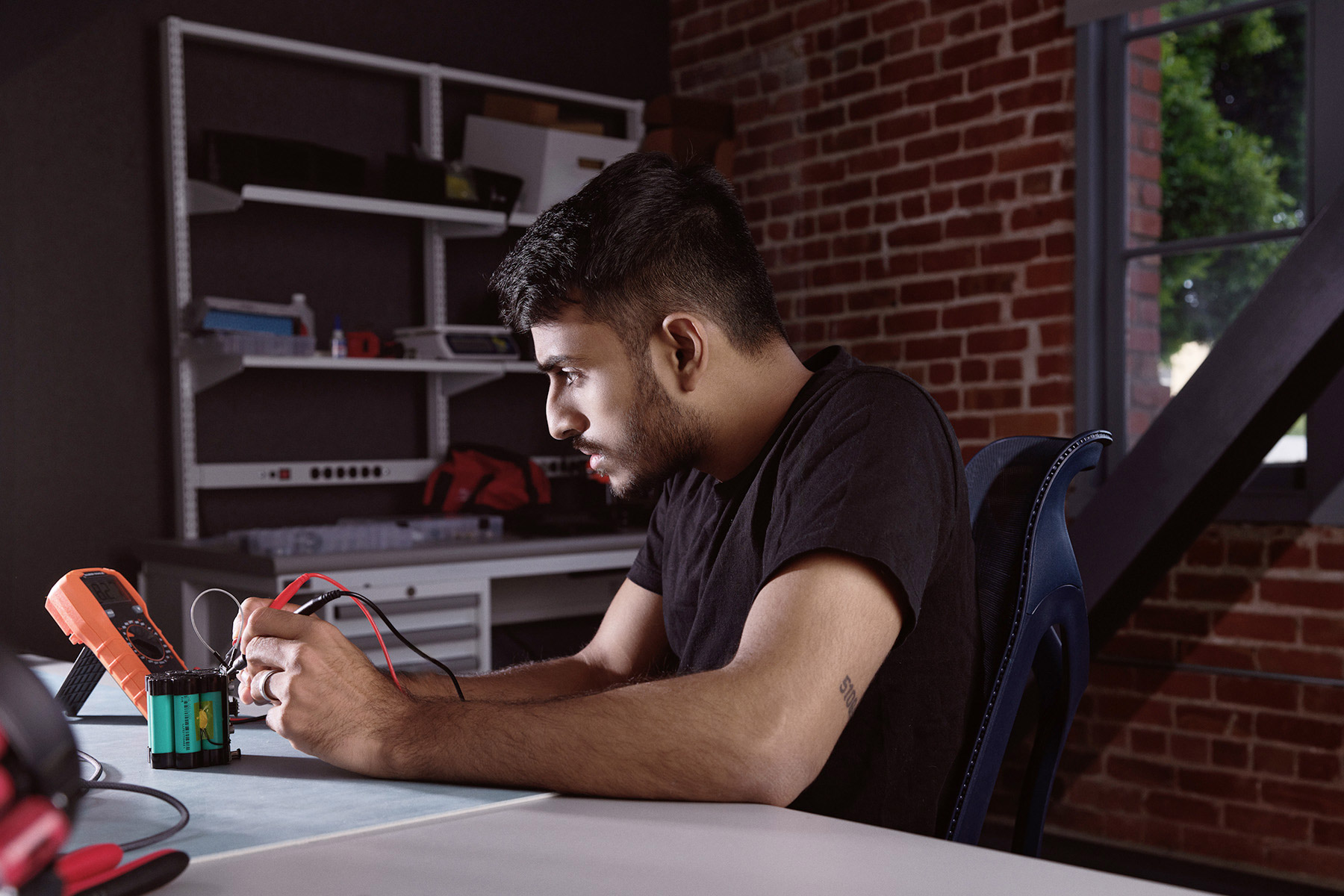 A focused individual working with electronic tools in a modern workspace, symbolizing innovation and technology.