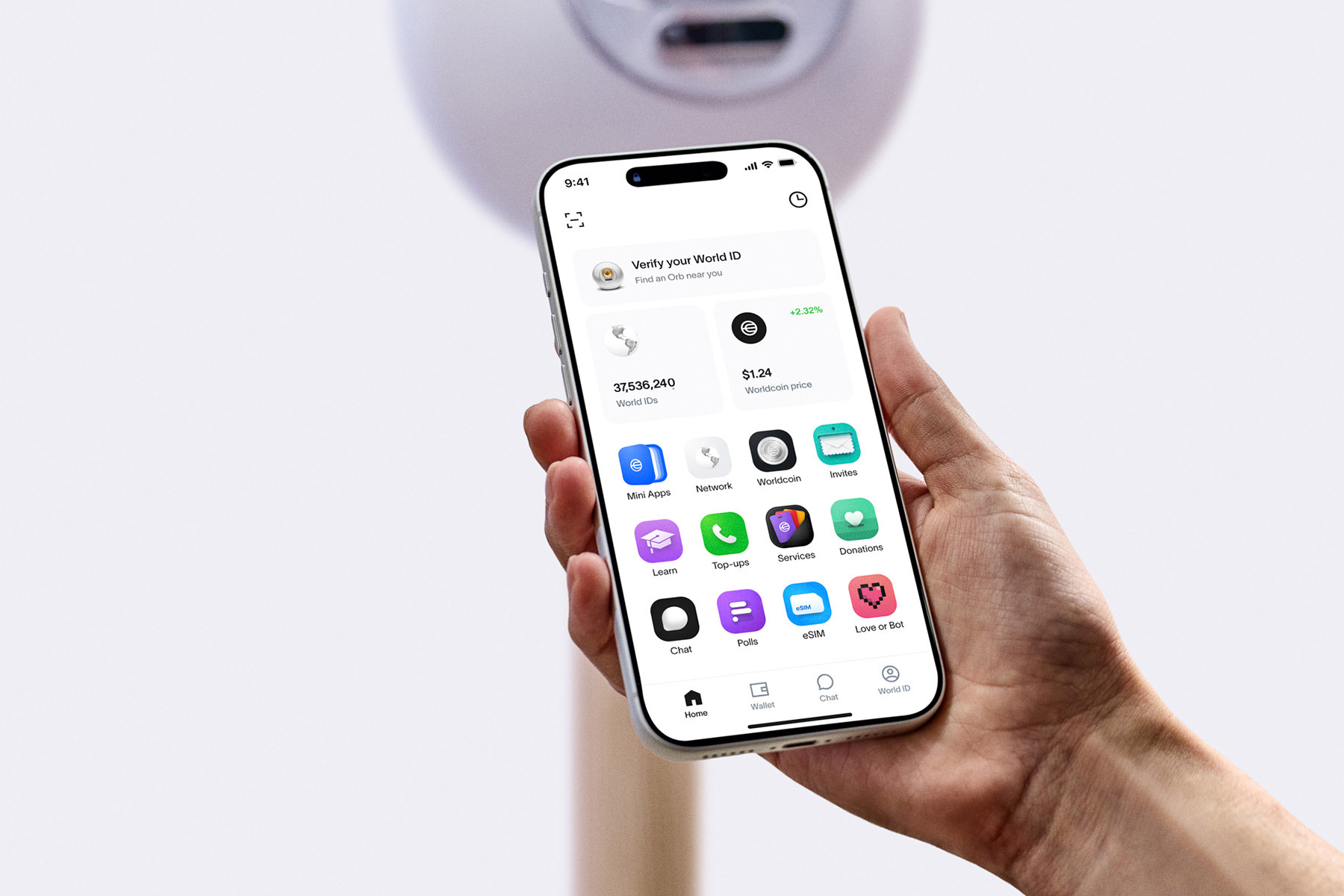 A hand holding a smartphone displaying the World App interface, with options for verifying World ID, alongside the Orb in the background.