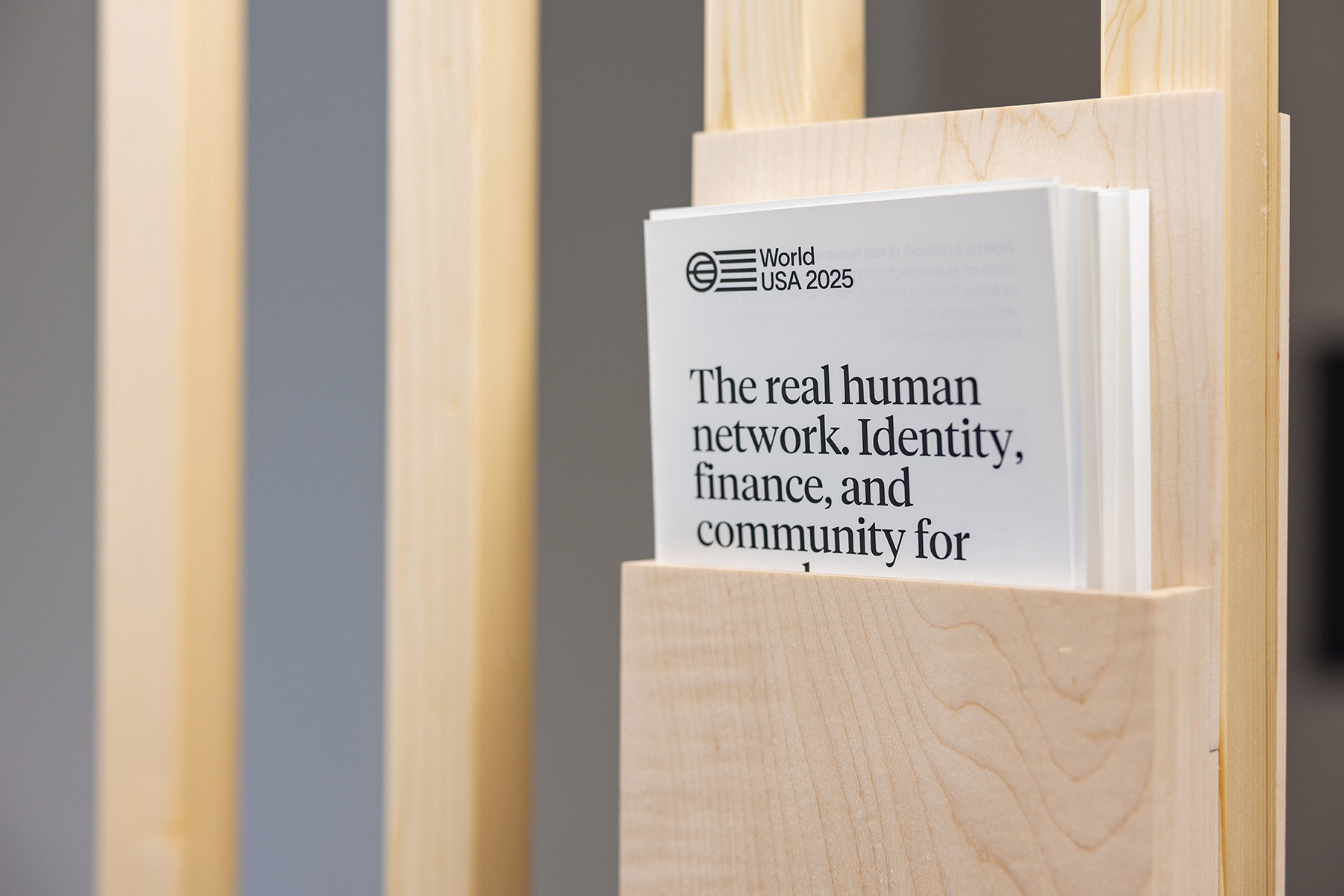 A brochure holder displaying a pamphlet titled 'The real human network. Identity, finance, and community for World USA 2025.'