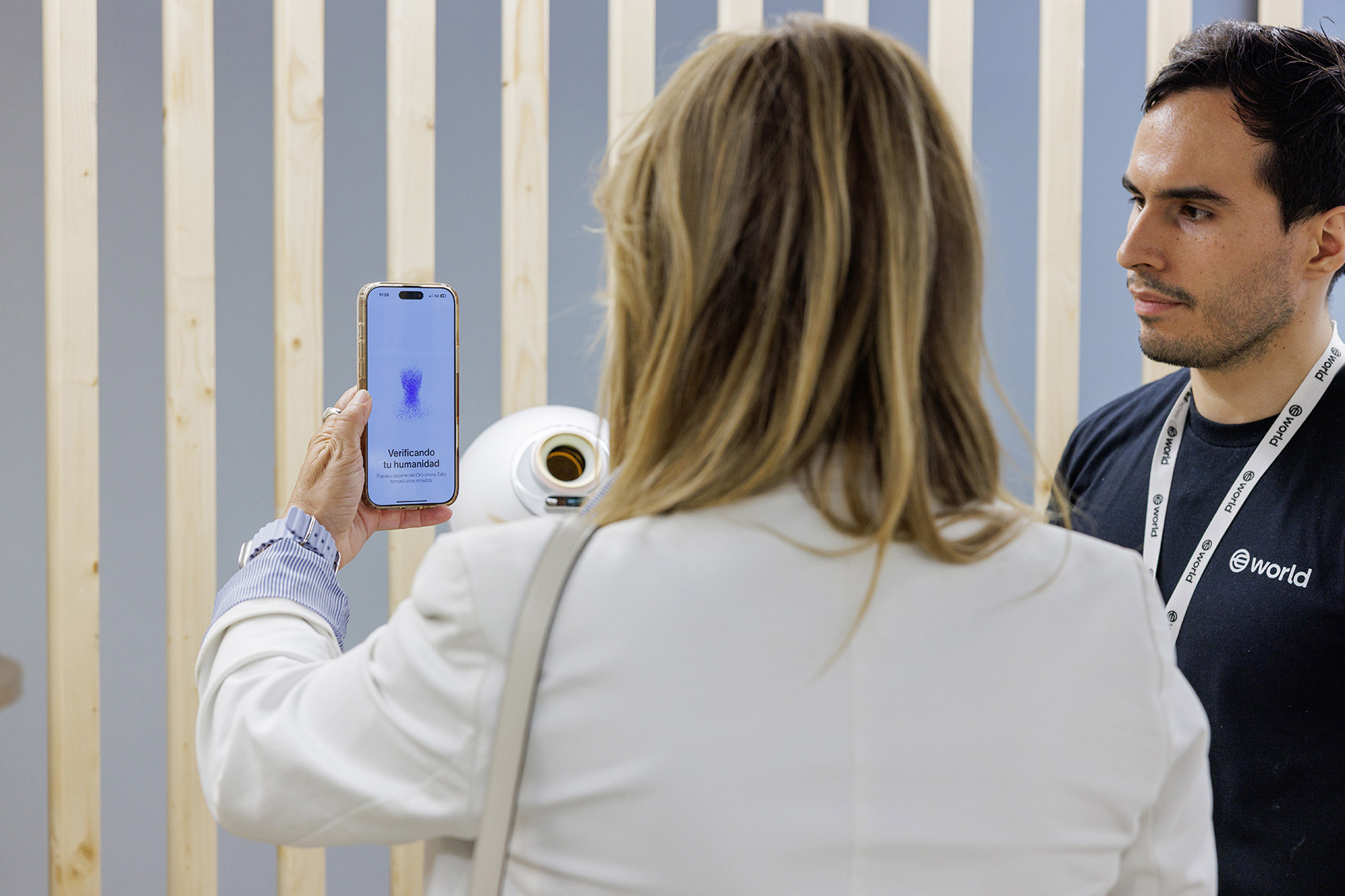A user verifies their identity on the World App while interacting with a representative. The app screen shows a verification interface.