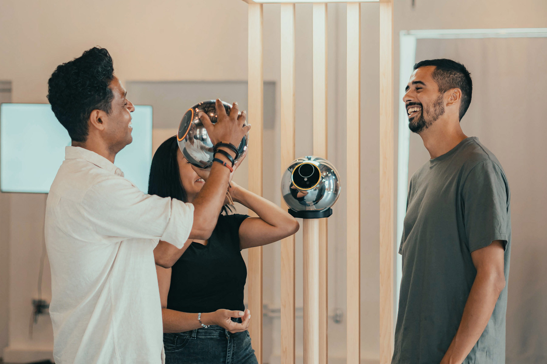 Two people are interacting with an Orb while a third person smiles in the background, showcasing a moment of biometric verification.