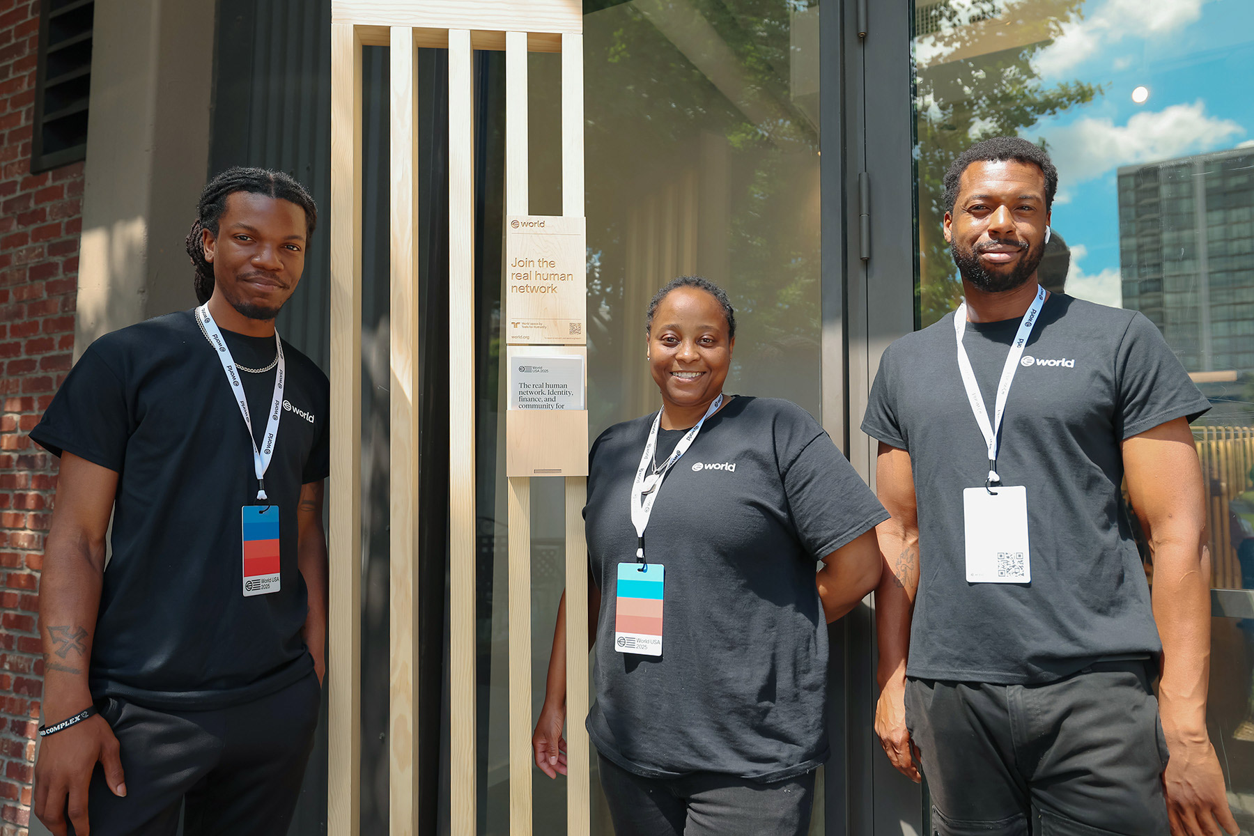 Three individuals smiling and standing in front of the World office, promoting community engagement and innovation.