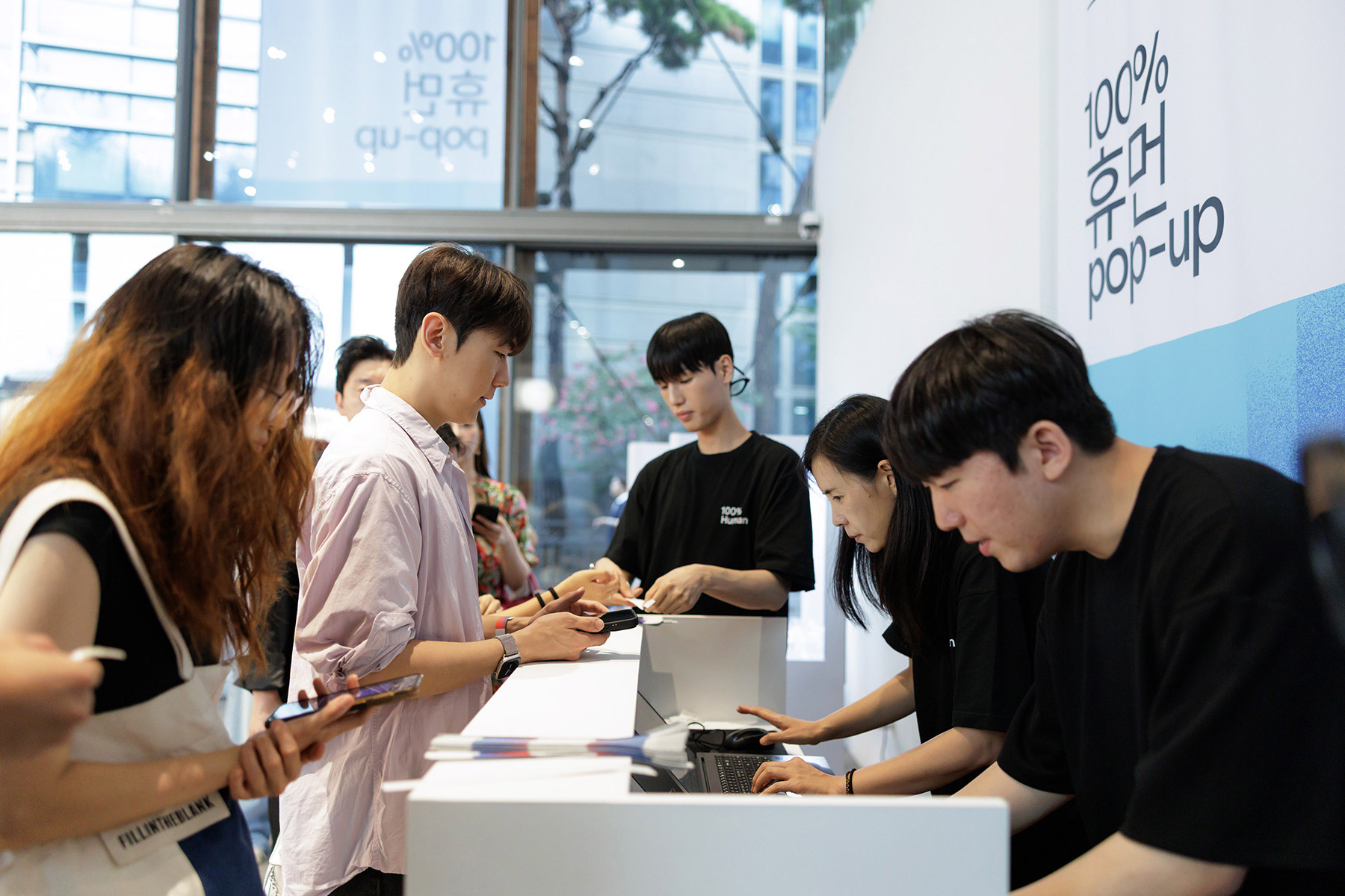 People engaging at a pop-up event, interacting with staff and using handheld devices, showcasing community involvement.