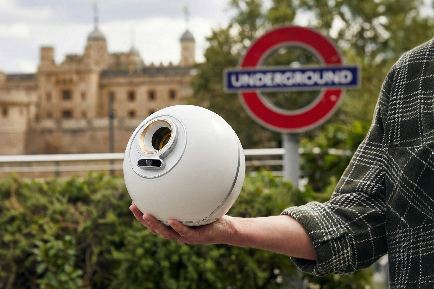 A person holding an Orb in front of the London Underground sign with the Tower of London in the background.