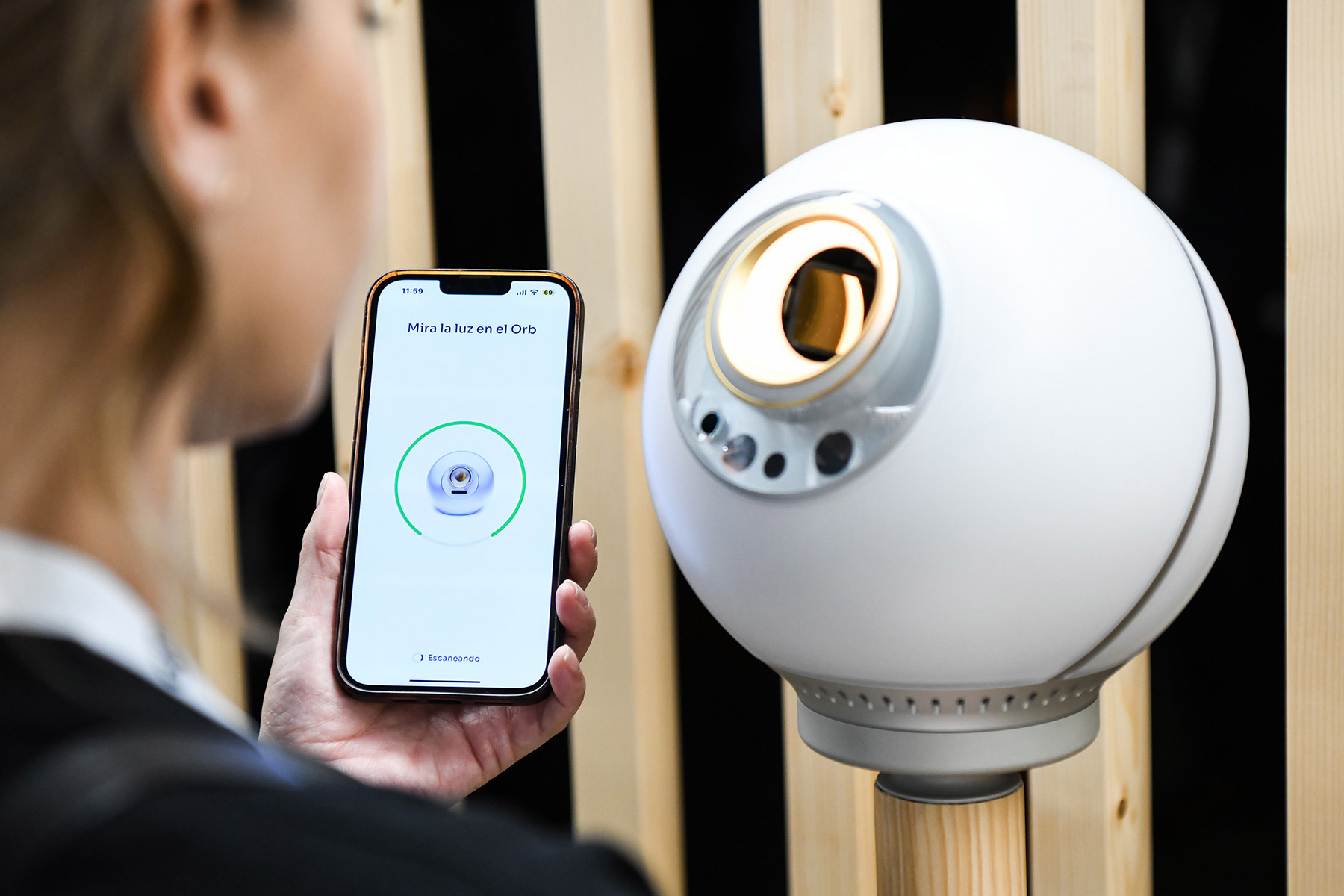 A person using a smartphone to interact with the Orb, which is displaying a verification screen.