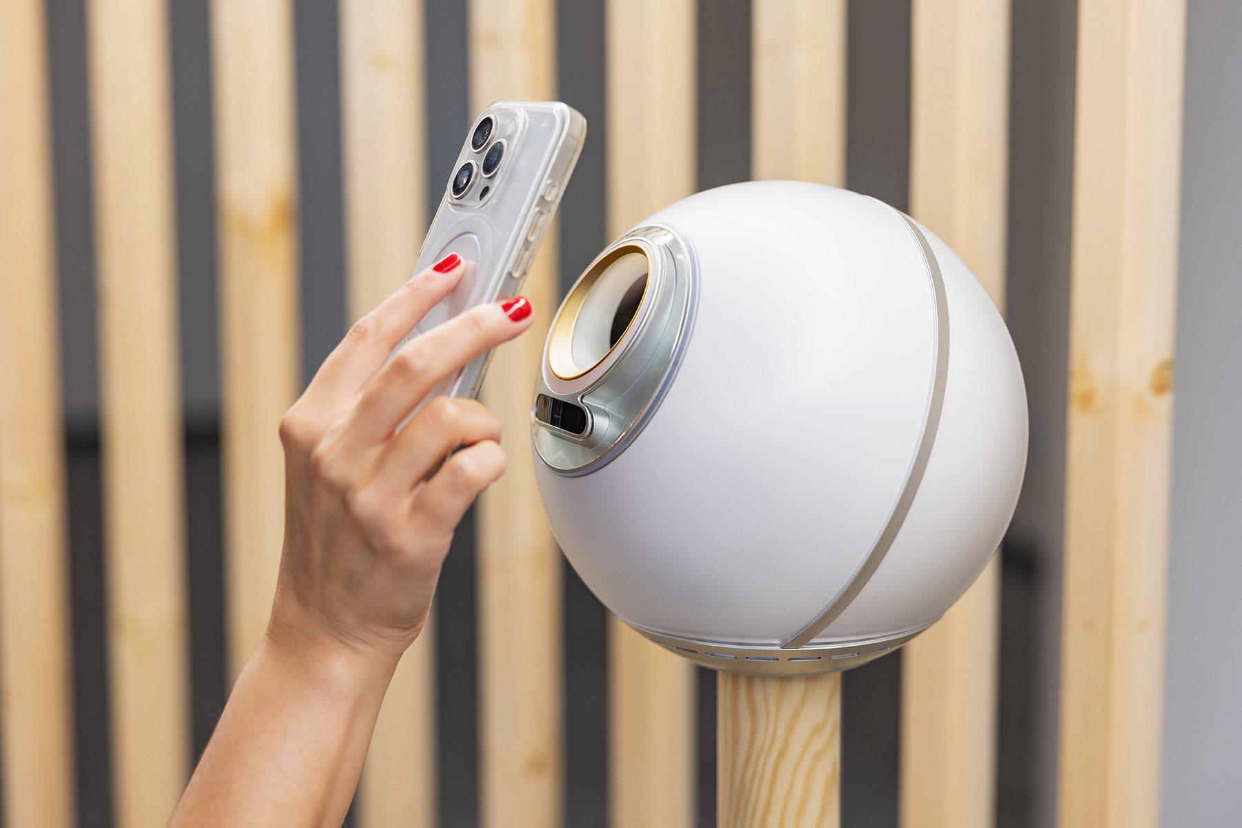 A person using a smartphone to verify with an Orb for biometric verification in a modern setting.