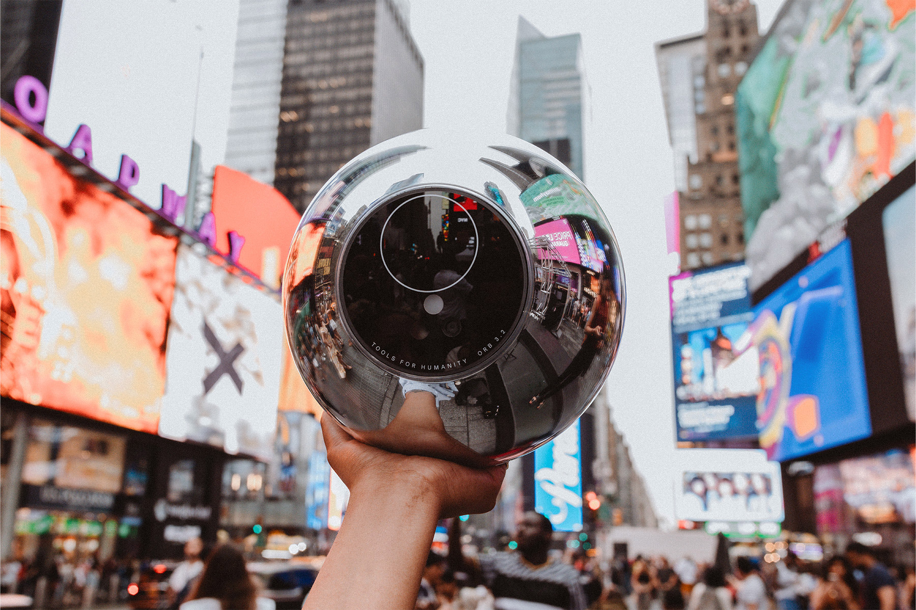A close-up of the Orb reflecting Times Square's bright signs, symbolizing its global tour for World ID registration.