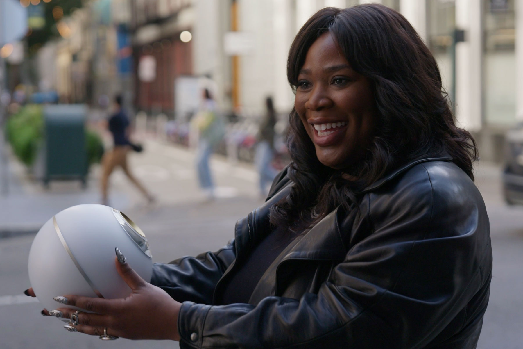 A smiling person holds an Orb while standing outdoors in a city, embodying a moment of verification and engagement with technology.