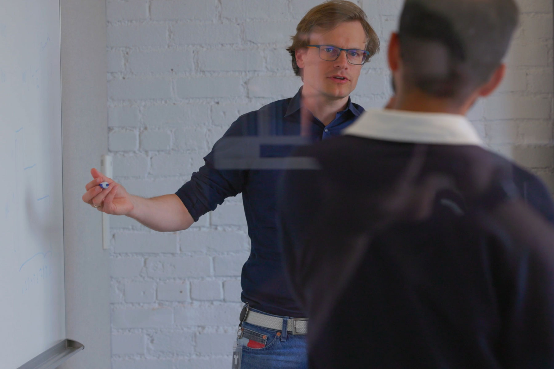 A man presenting to another person in an office setting, discussing concepts related to Worldcoin.