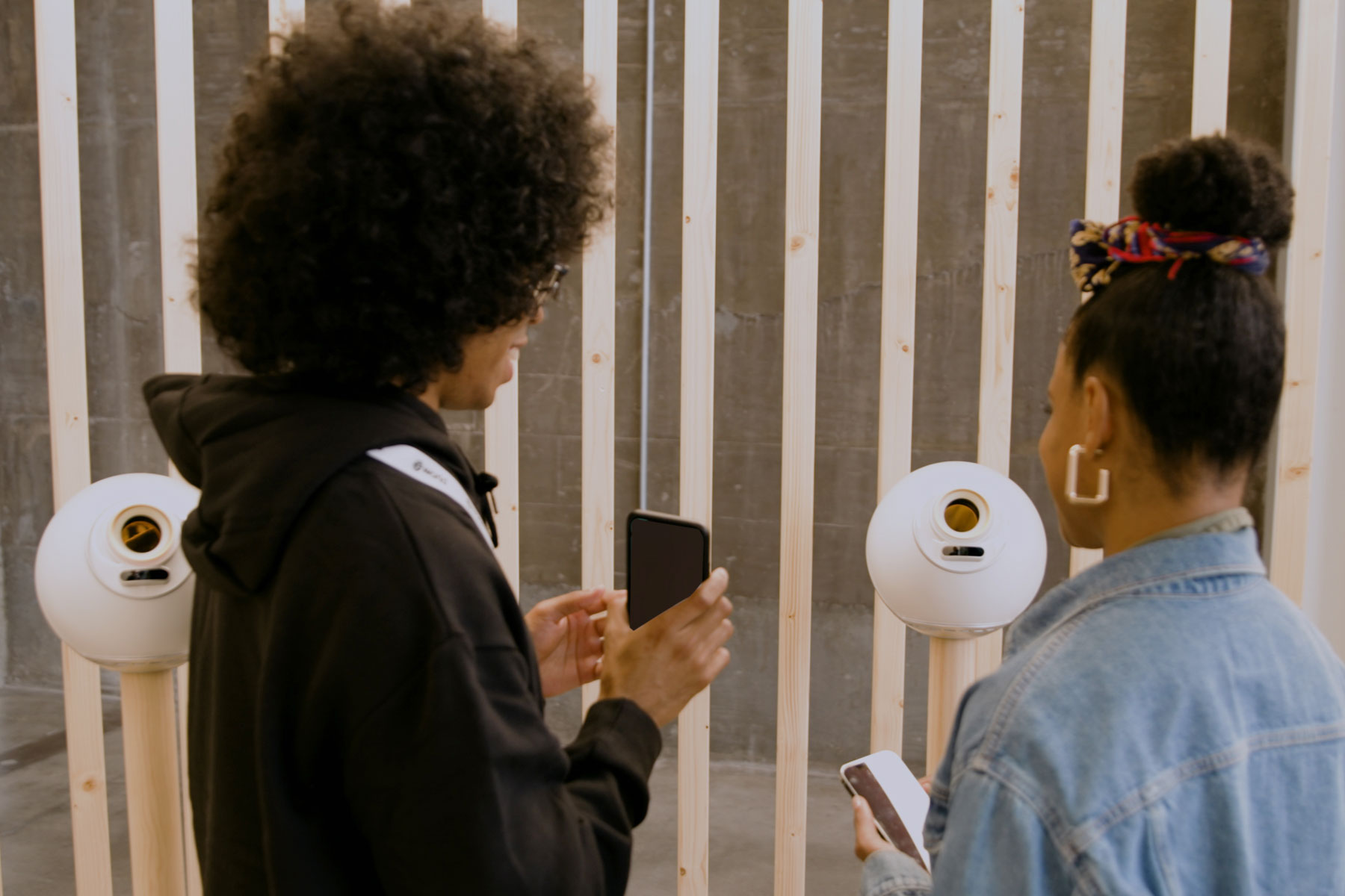 Two people using their smartphones while interacting with Orbs in a modern setting.