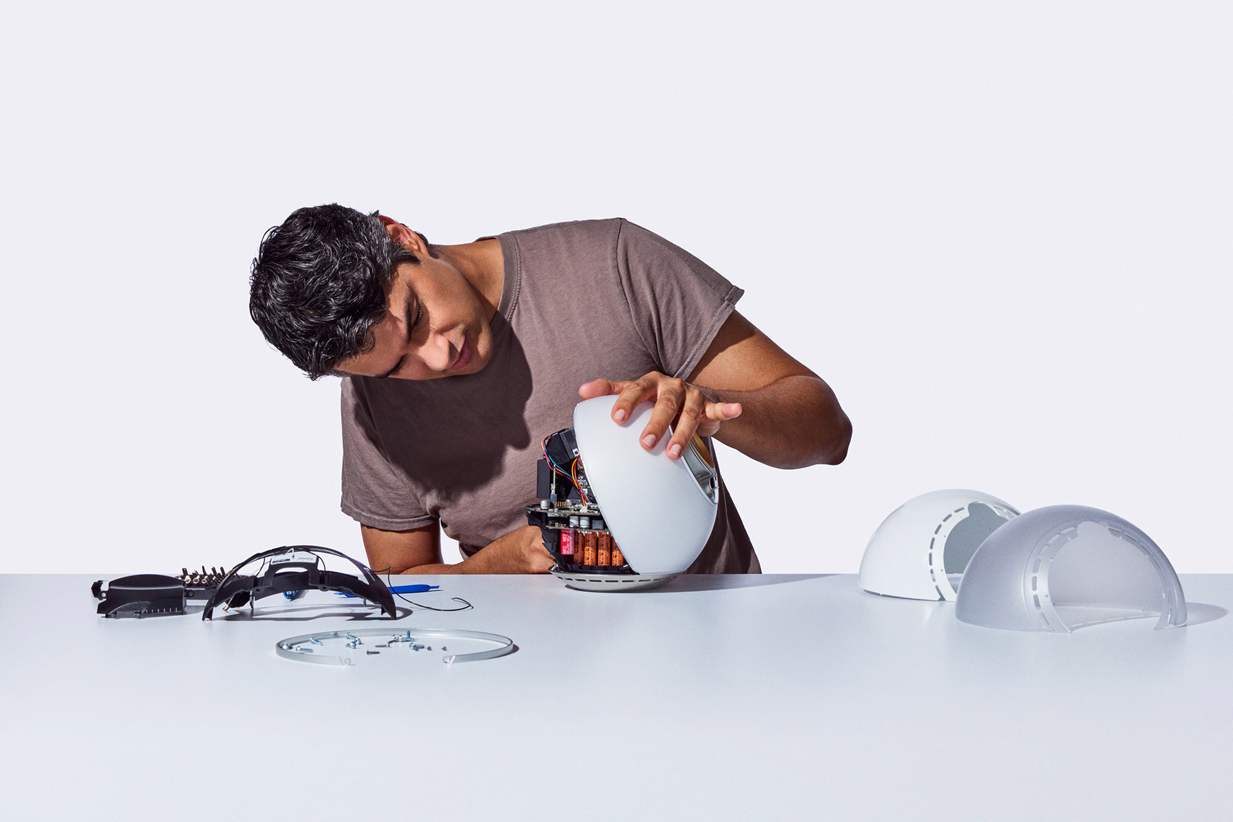 A person is assembling the Orb, focusing on its inner components, with several Orb parts on the table around them.
